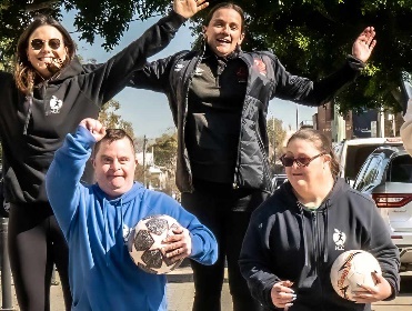 A group of people smiling and cheering outdoors.