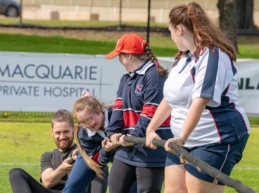 A group of people playing tug of war outdoors together.