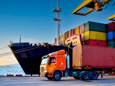 A truck and ship with shipping containers on it.