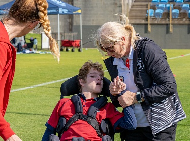 A person supporting someone else. They are outdoors at a community event.